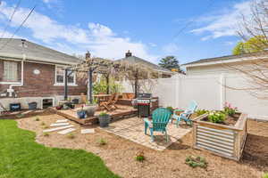 Fenced backyard featuring a patio area, grilling area, a deck, and a vegetable garden