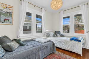 Bedroom with dark wood finished floors and multiple windows