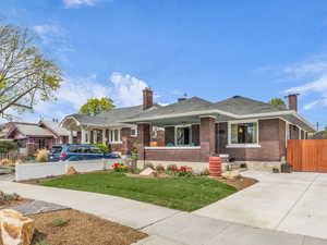 Bungalow-style home featuring a chimney, brick siding, concrete driveway, and an outbuilding
