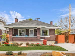 Bungalow-style house featuring a chimney, brick siding, and covered porch
