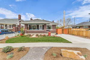 Bungalow with brick siding, a porch, a chimney, and driveway