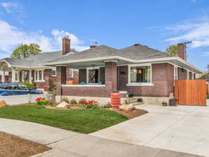 View of front facade with a chimney, a porch, and brick siding