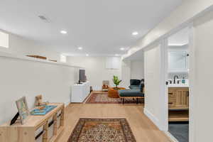 Living area with light wood finished floors and recessed lighting