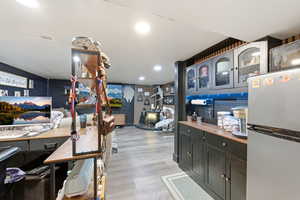 Kitchen with glass insert cabinets, freestanding refrigerator, recessed lighting, light wood-type flooring, and butcher block countertops