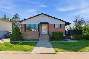 Bungalow-style home with a front yard and brick siding