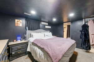 Bedroom with light colored carpet, a textured ceiling, recessed lighting, and connected bathroom