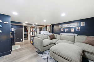 Home theater room with light wood-type flooring, washer / clothes dryer, and recessed lighting