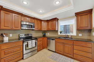 Kitchen featuring stainless steel appliances, wood finish cabinets, granite countertops, and crown molding.