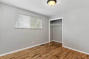 Unfurnished bedroom with wood finished floors, a closet, and a textured ceiling