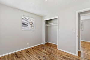 Unfurnished bedroom featuring light wood finished floors, a textured ceiling, and a closet