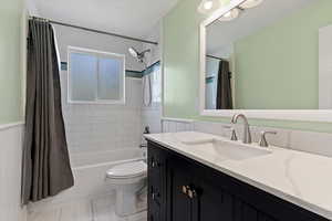 Bathroom featuring vanity, a wainscoted wall, and shower / bathtub combination with curtain