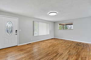 Entryway with wood-type flooring and a textured ceiling