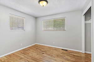 Unfurnished bedroom with a closet, light wood finished floors, and a textured ceiling