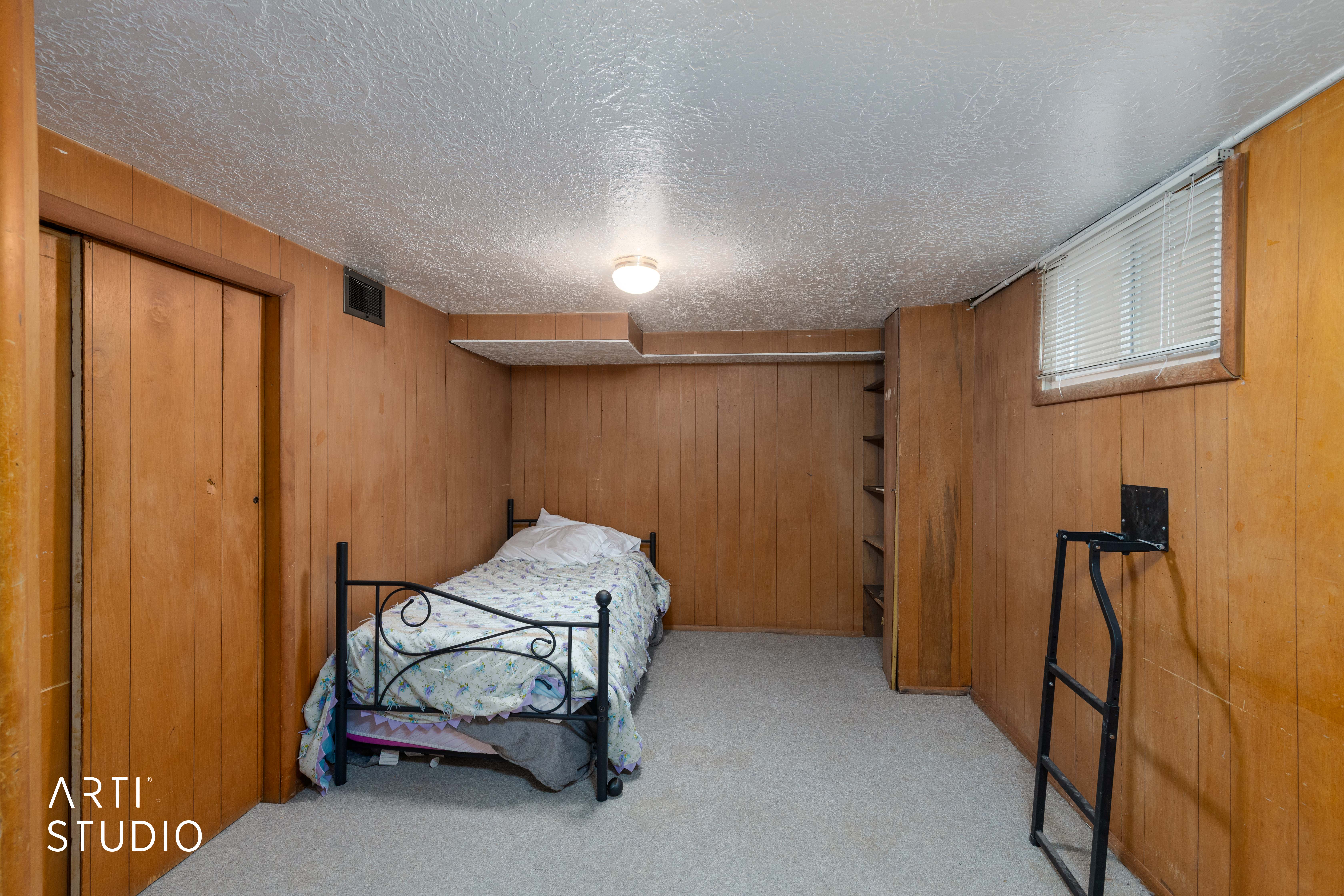 Bedroom with a closet, light carpet, wooden walls, and a textured ceiling