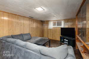 Living area featuring wood walls and a textured ceiling