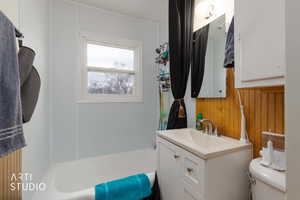 Full bath with vanity and wooden walls