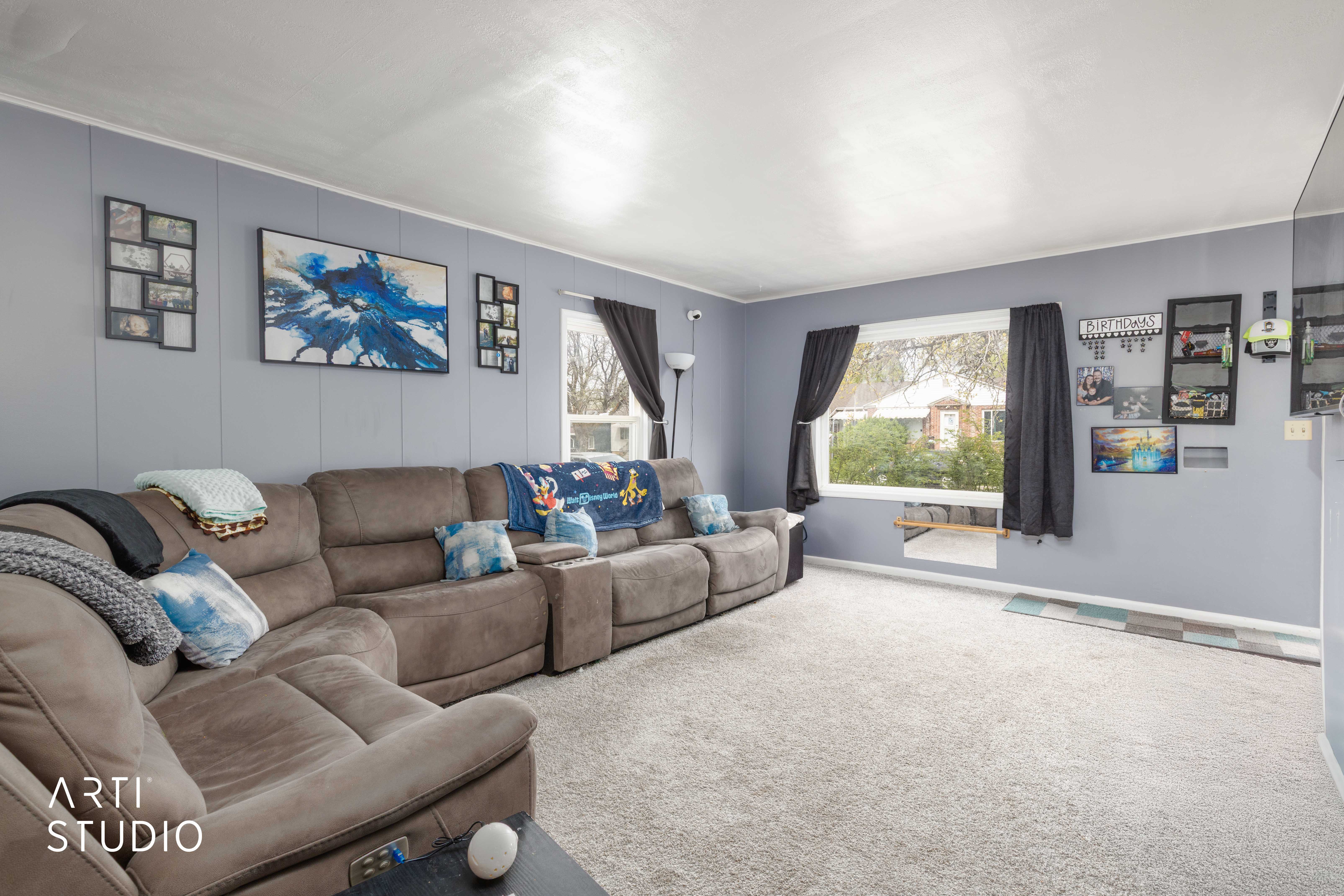 Carpeted living area with a decorative wall and baseboards