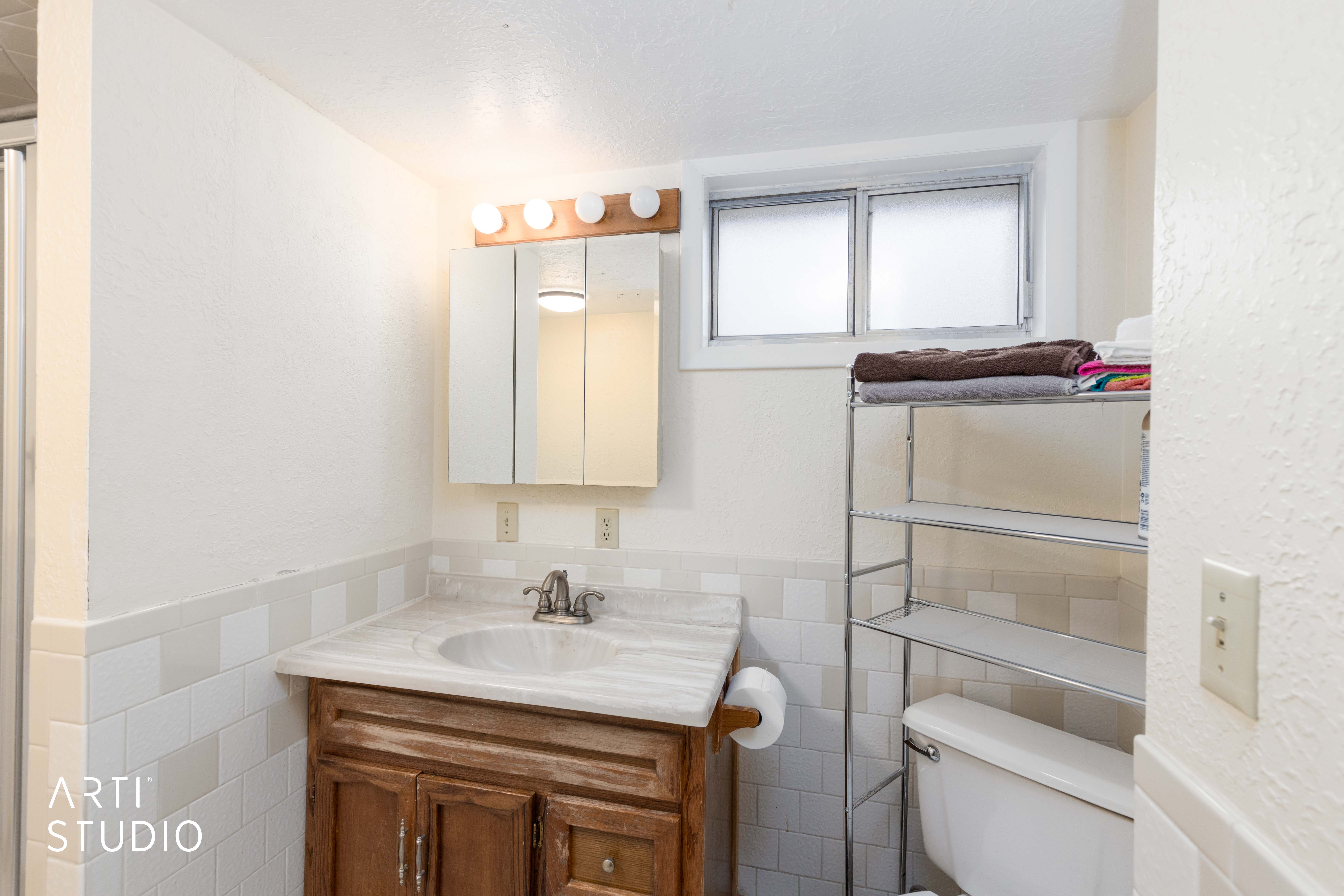 Bathroom with vanity, a textured wall, tile walls, and a wainscoted wall
