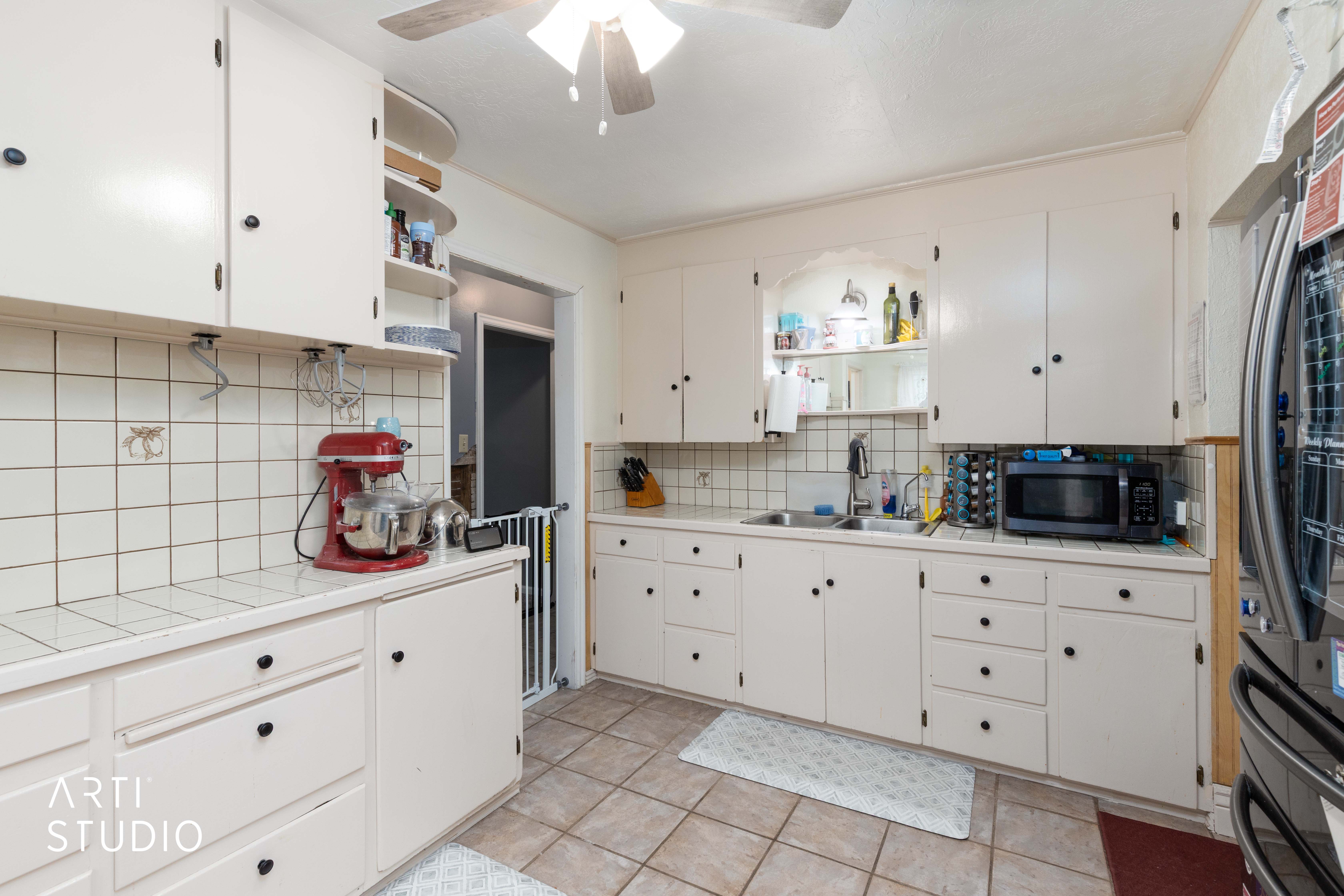 Kitchen with tile counters, open shelves, and backsplash