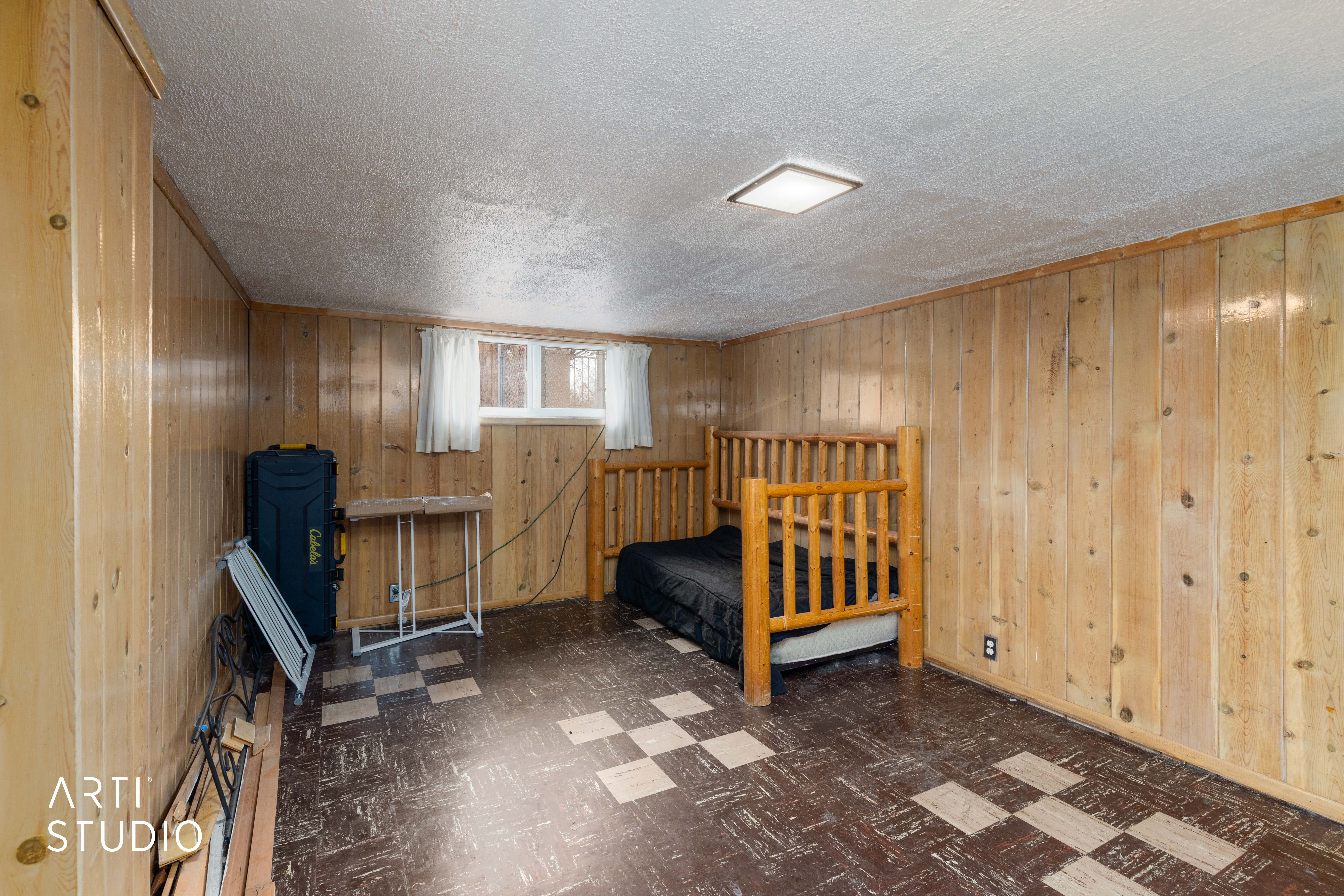 Bedroom with dark flooring and wooden walls