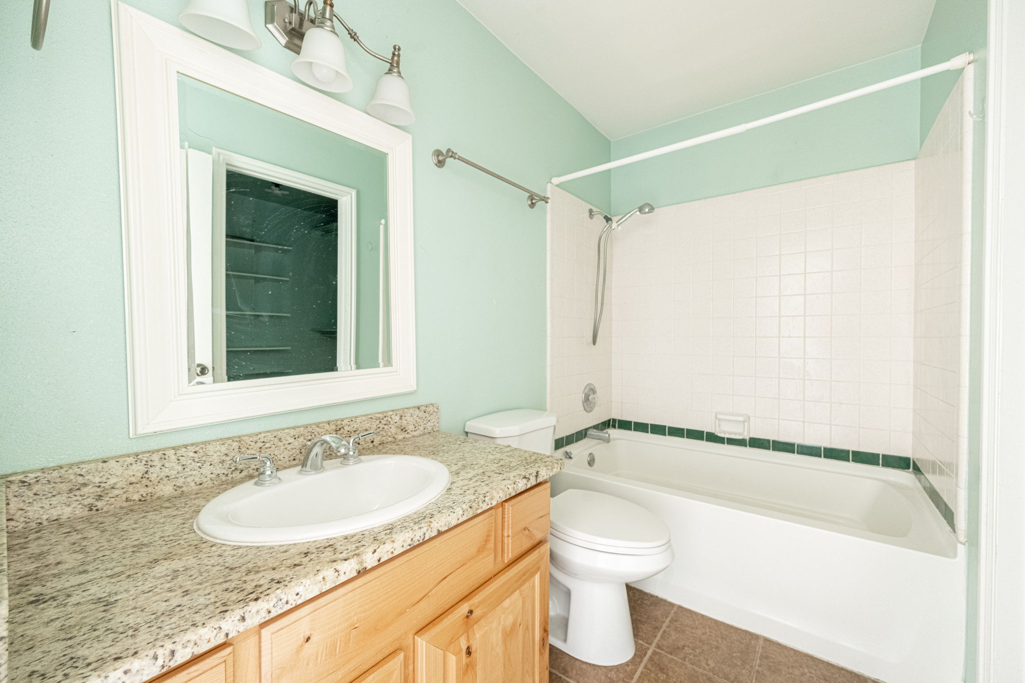 Bathroom featuring a wood-finish vanity with a light granite countertop
