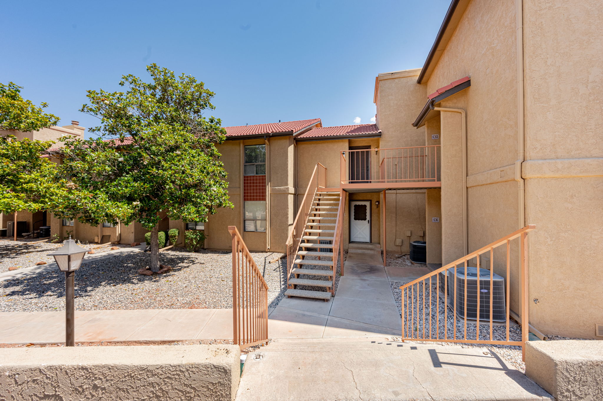 Multi-level stucco exterior featuring a terra cotta tile roof and a second-story balcony