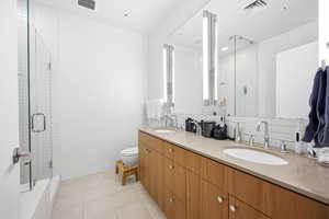 Full bathroom featuring double vanity, a stall shower, and light tile patterned flooring
