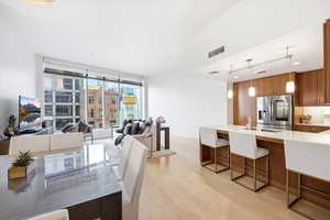Kitchen featuring a kitchen bar, light stone countertops, open floor plan, and stainless steel refrigerator with ice dispenser