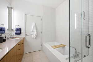 Full bathroom featuring a bath, double vanity, light tile patterned floors, and a shower stall