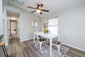 Dining area with vaulted ceiling, a ceiling fan, and dark wood-style floors