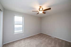 Empty room featuring light carpet and a ceiling fan