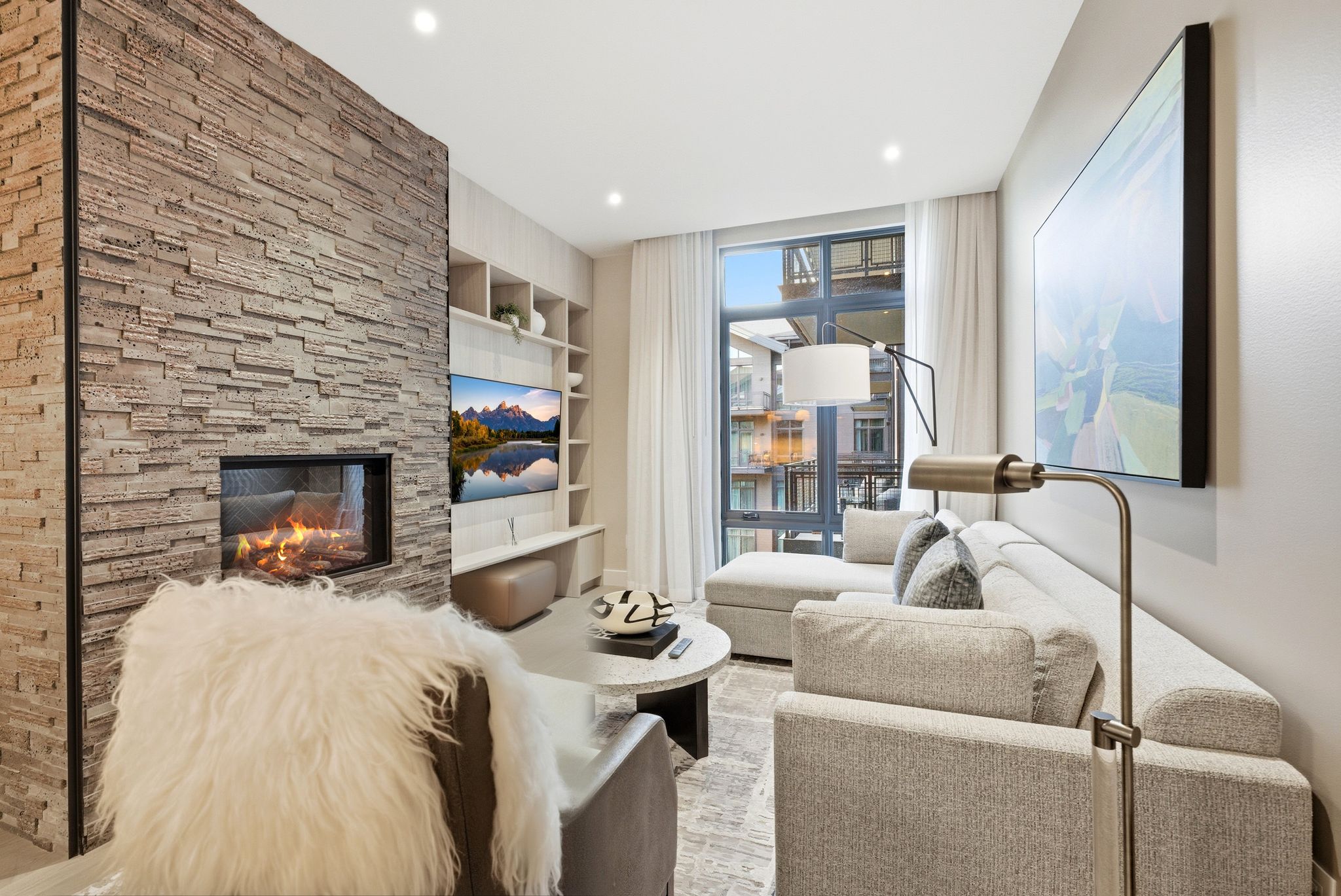 Living area featuring built in features, a stone fireplace, recessed lighting, and expansive windows