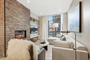 Living area featuring built in features, a stone fireplace, recessed lighting, and expansive windows