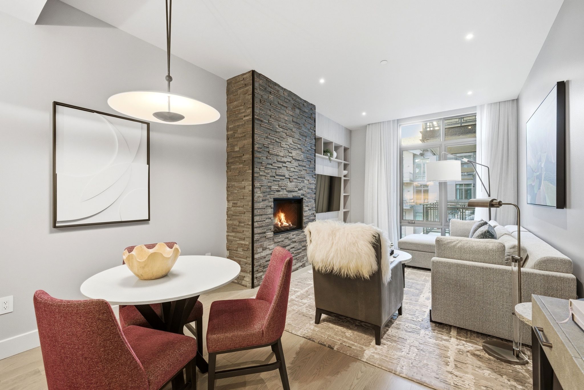 Dining space featuring light wood finished floors, built in shelves, a stone fireplace, and recessed lighting