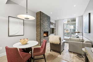 Dining space featuring light wood finished floors, built in shelves, a stone fireplace, and recessed lighting