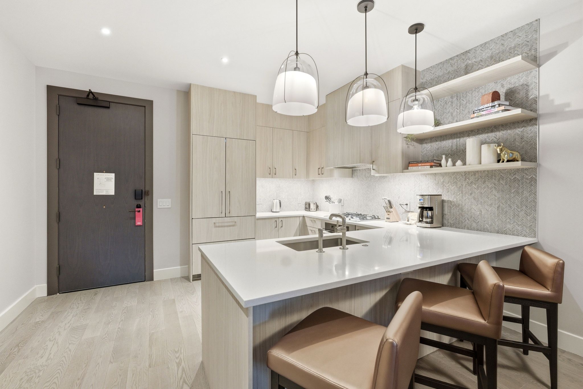 Kitchen with light wood finish cabinets, a kitchen bar, a peninsula, open shelves, and pendant lighting