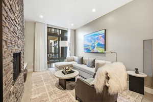 Living area with floor to ceiling windows, a heating unit, light wood-style floors, a fireplace, and recessed lighting
