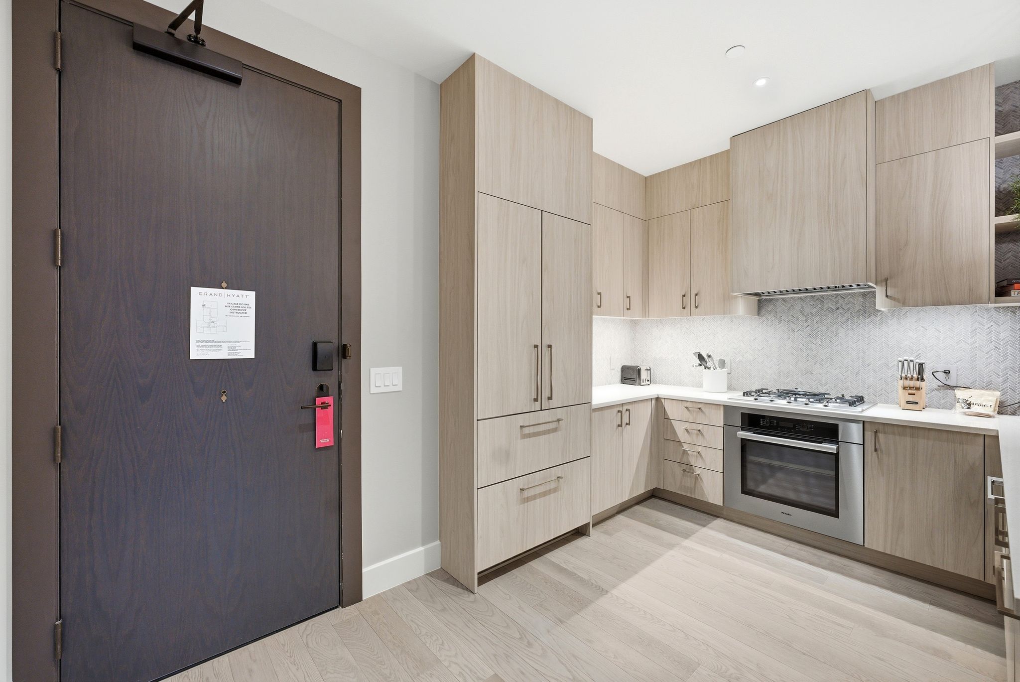 Kitchen featuring light wood finish cabinetry, modern cabinets, stainless steel appliances, and backsplash