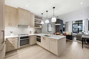 Kitchen featuring light wood finish cabinetry, a peninsula, modern cabinets, open shelves, and stainless steel appliances