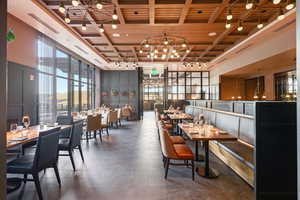 Dining area with wood ceiling, a decorative wall, hanging lights, high coffered ceiling, and healthy amount of natural light