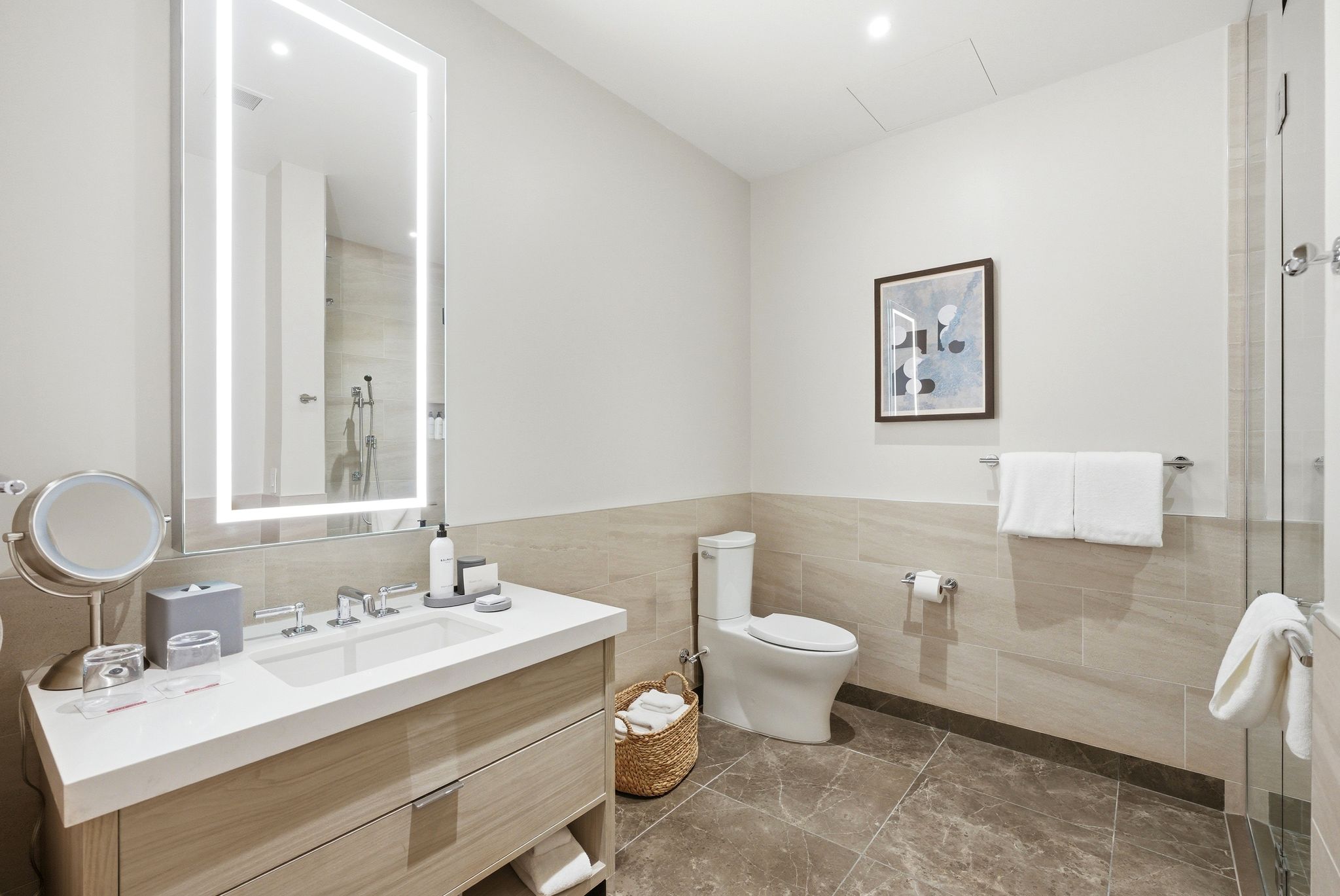 Bathroom featuring vanity, a tile shower, tile walls, and wainscoting