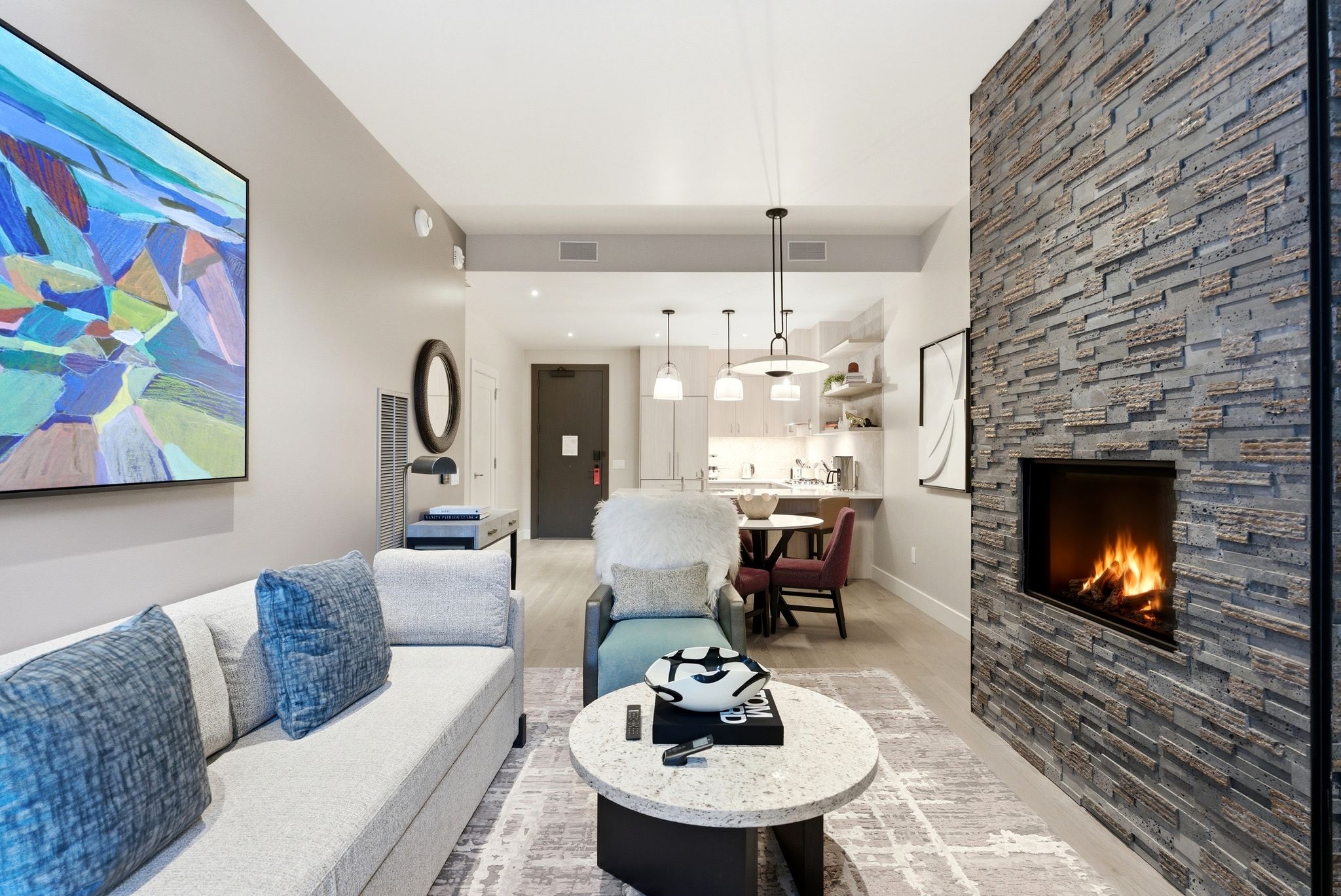 Living room with a stone fireplace and light wood-style floors