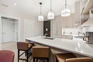 Kitchen featuring light wood finish cabinets, a peninsula, a kitchen bar, modern cabinets, and light stone countertops