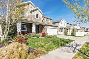 View of front of home featuring board and batten siding, stone siding, concrete driveway, covered porch, and a residential view