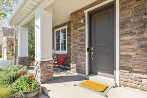 Entrance to property featuring a porch and stone siding