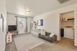 Living area featuring light carpet and washing machine and clothes dryer