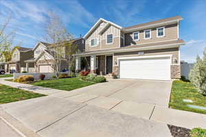 Craftsman house featuring board and batten siding, stone siding, a front yard, a porch, and driveway