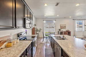 Kitchen with dark wood finish cabinetry, stainless steel appliances, recessed lighting, dark wood finished floors, and a textured ceiling