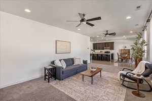 Living room featuring recessed lighting, light carpet, and a ceiling fan