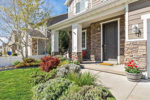 Doorway to property with covered porch and stone siding